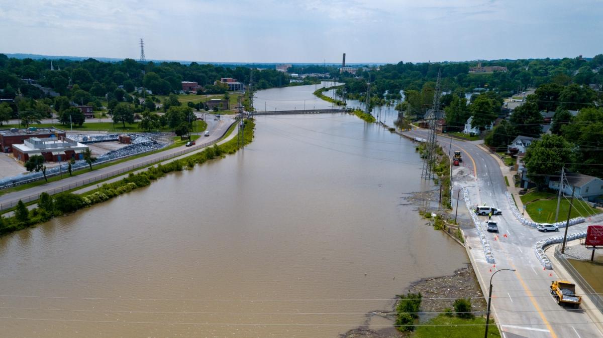 An aerial image of a muddy river running through a town lined with trees.