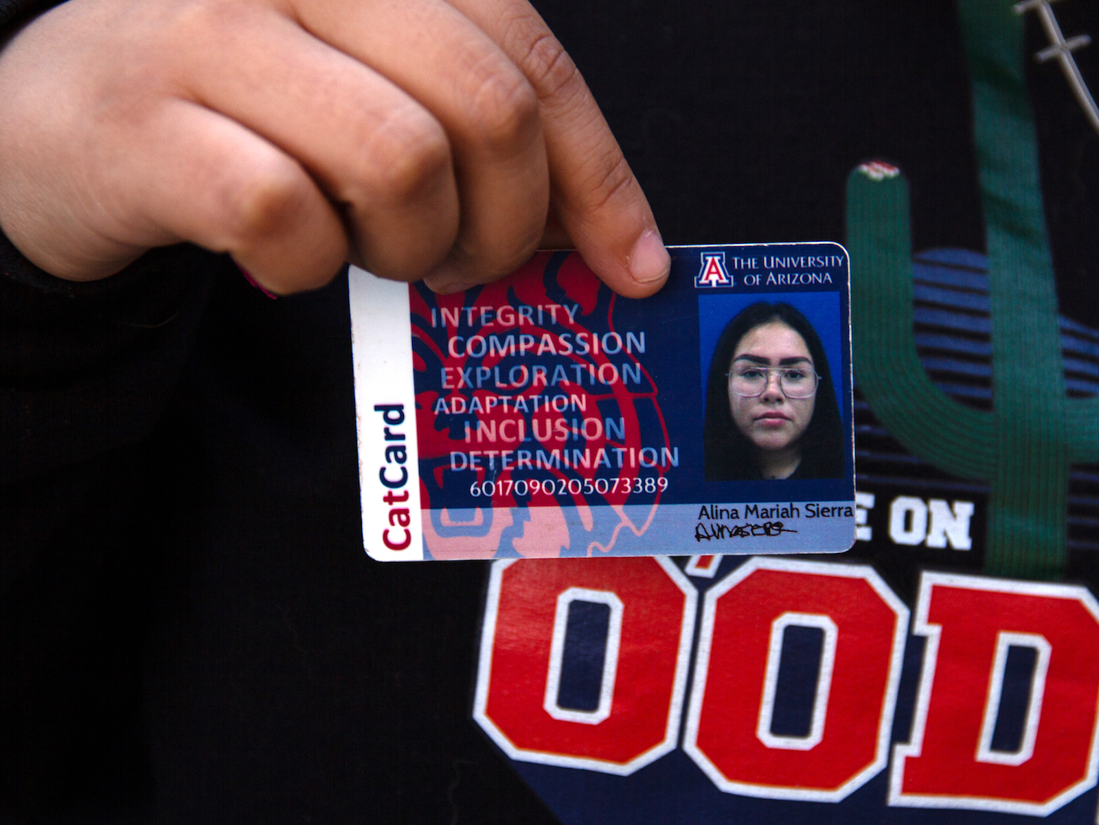 a hand holds an ID card with a photo and ID number