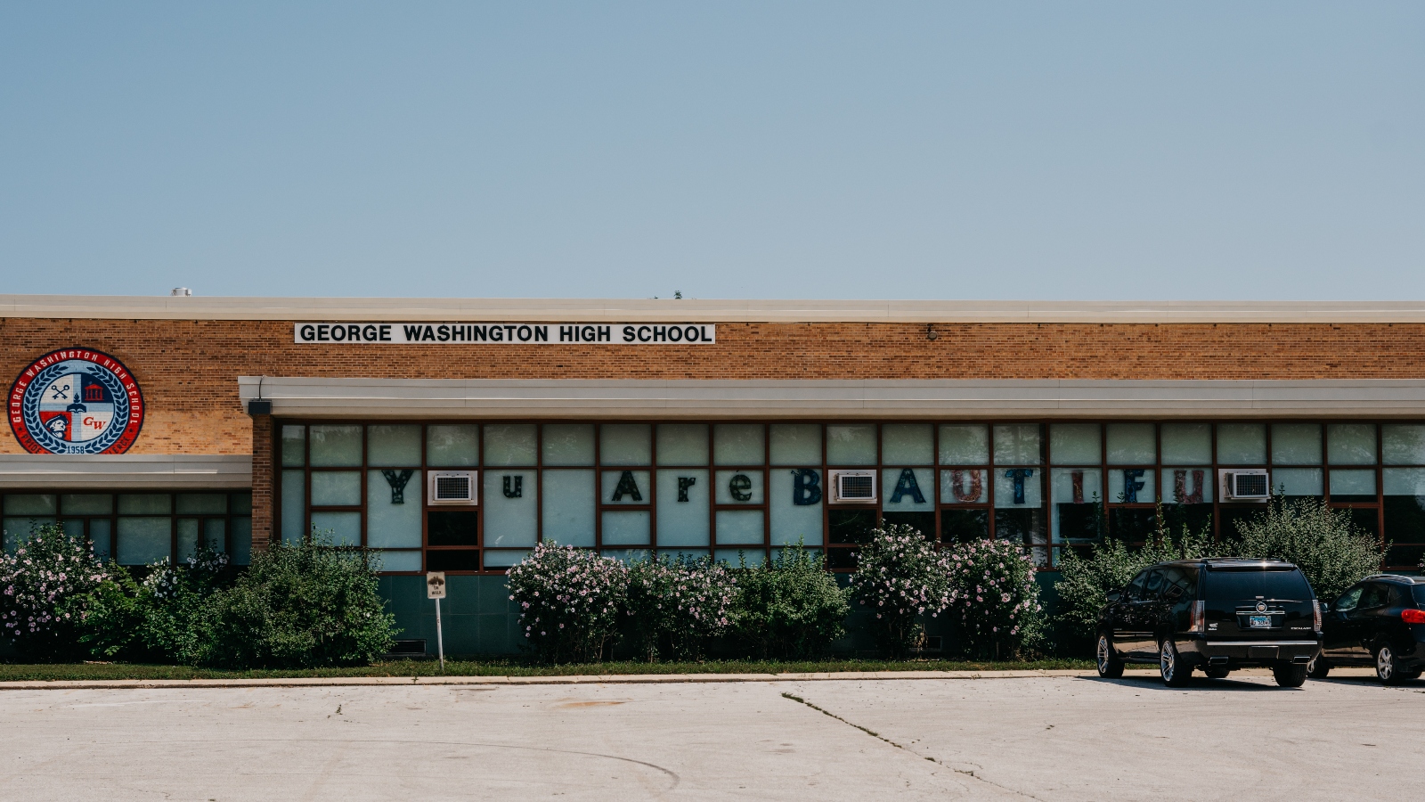 The front of George Washington High School with the letters 'You Are Beautiful' in the windows.