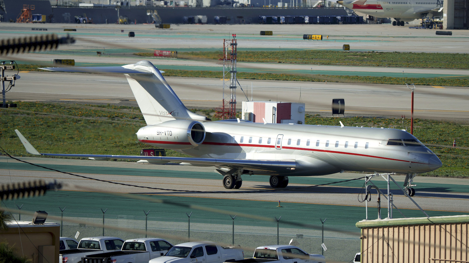 a silver plane with a red stripe on an airport tarmac