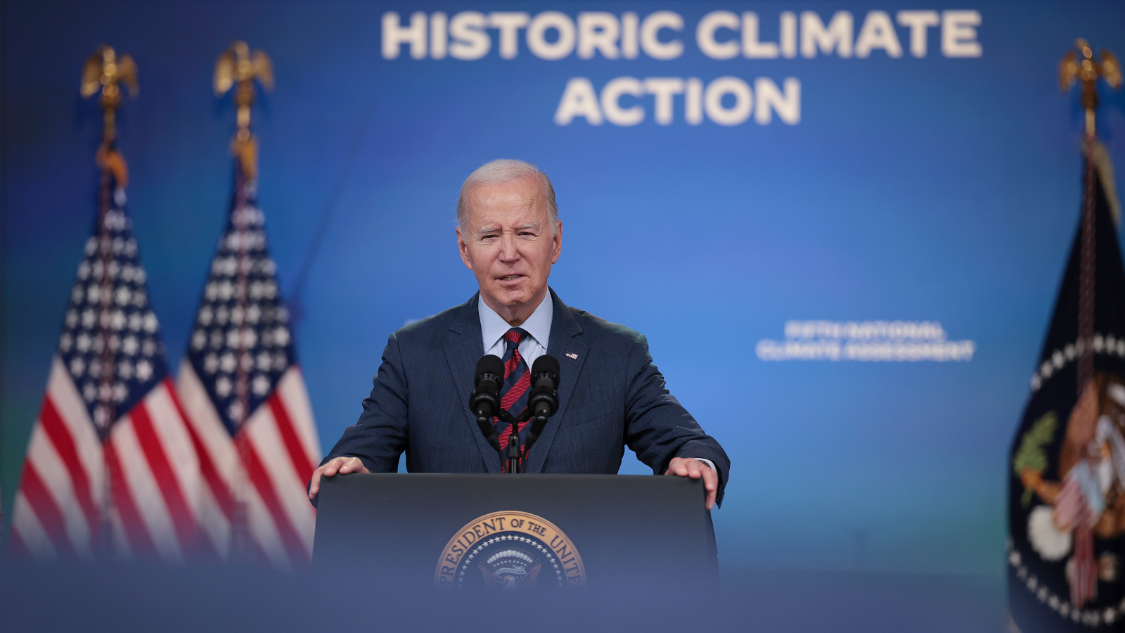 Photo of President Biden in front of a podium next to two American flags