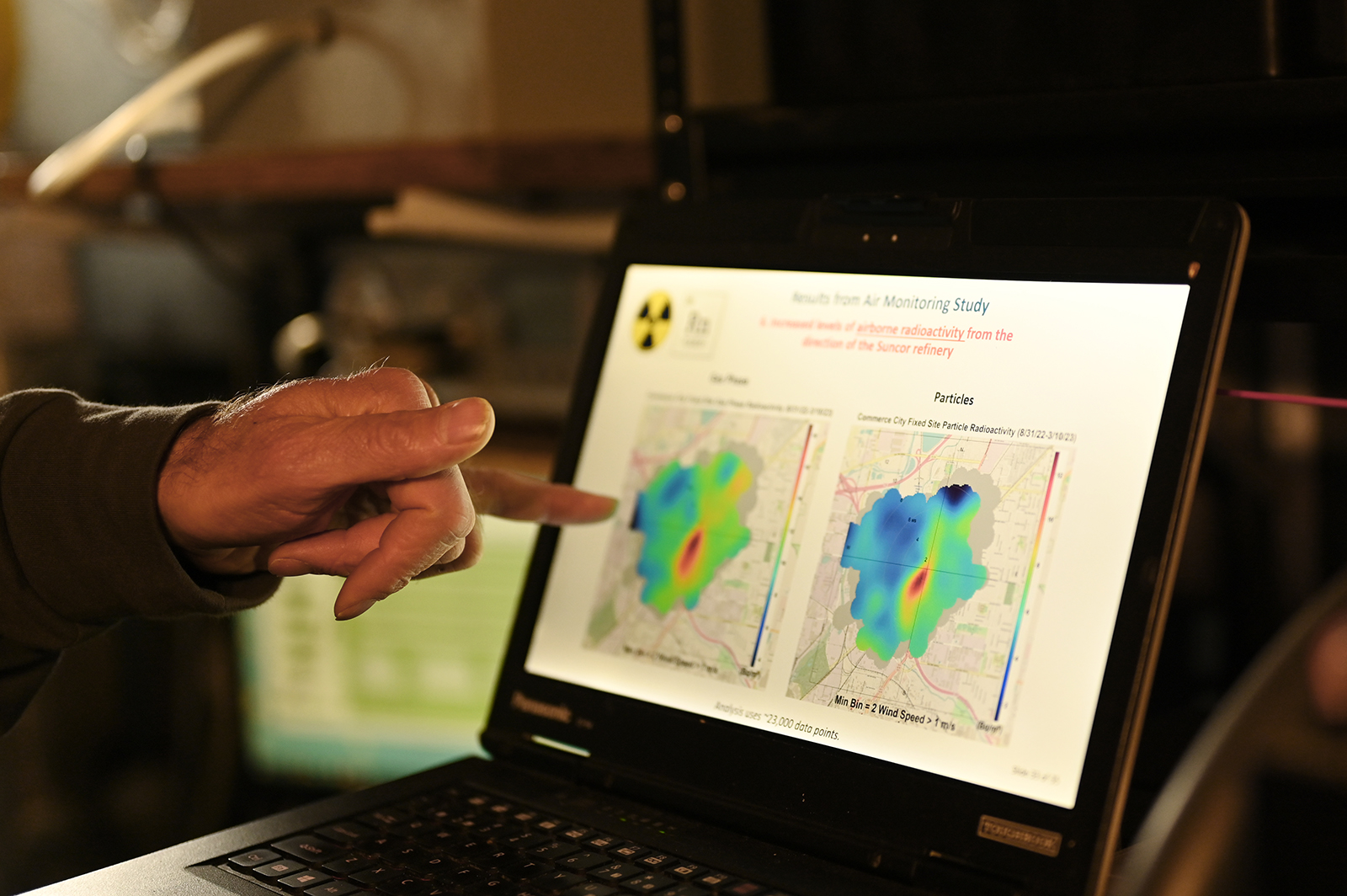 A hand points to a color-coded map of air pollution on a laptop screen.