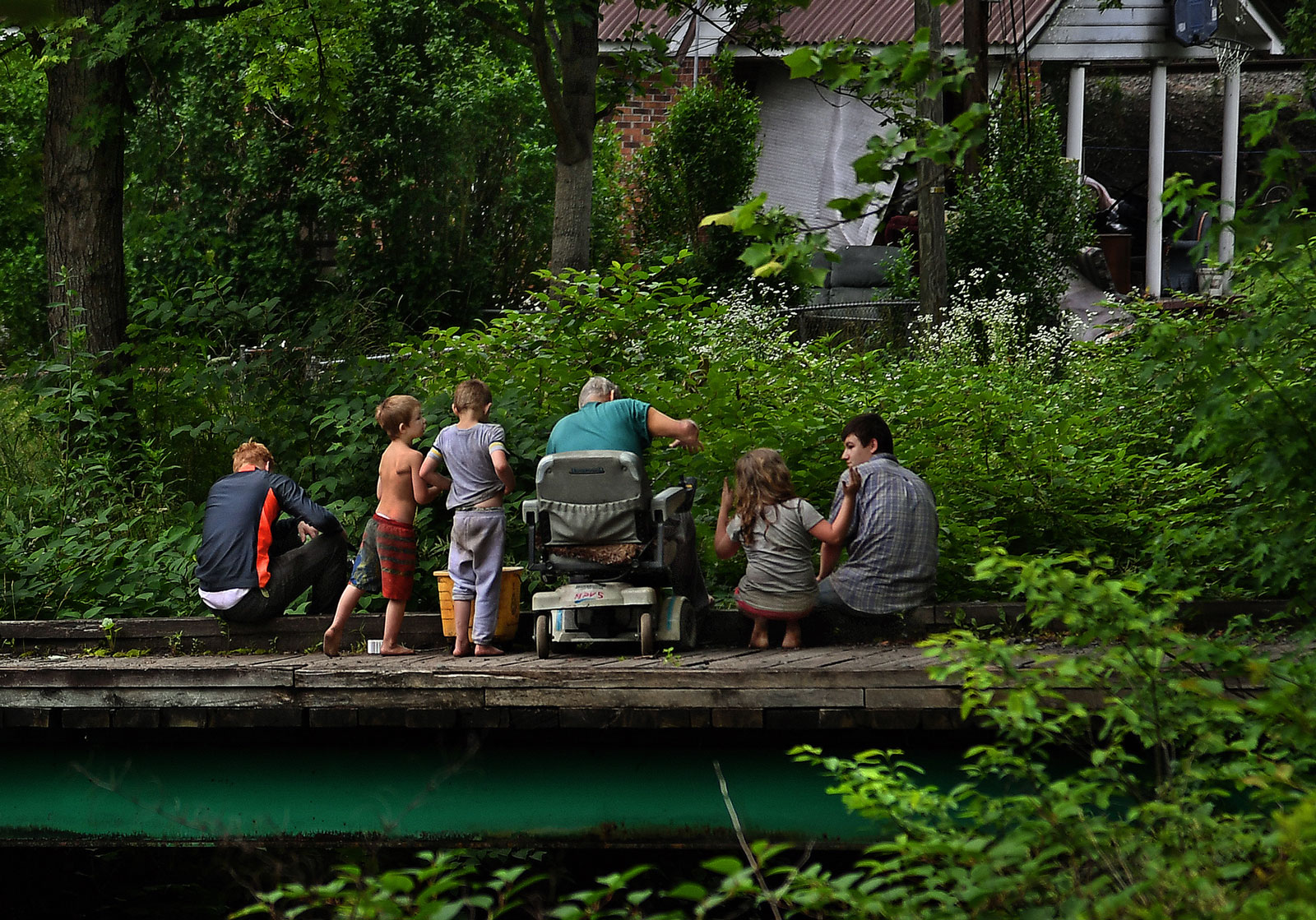 An older man teaches kids how to fish