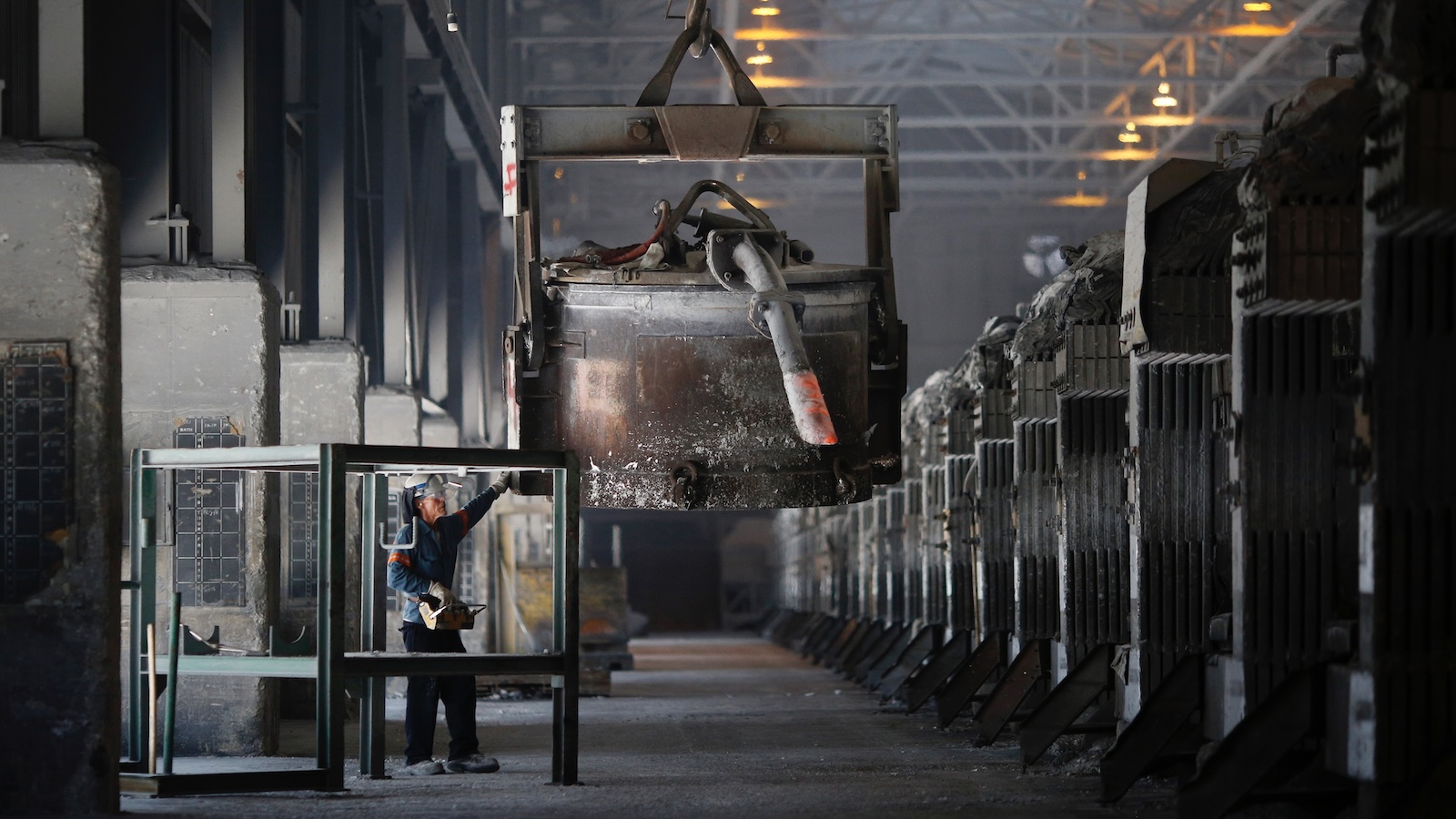 A factory worker guides an enormous cask of molten aluminum across the floor of a smelting factory in Kentucky.