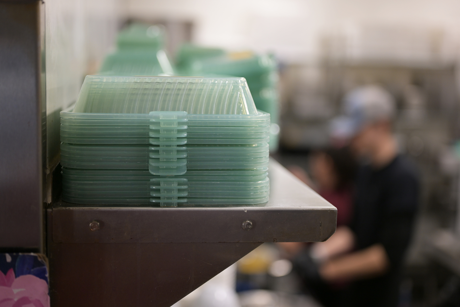 A stack of greenish reusale containers on a shelf