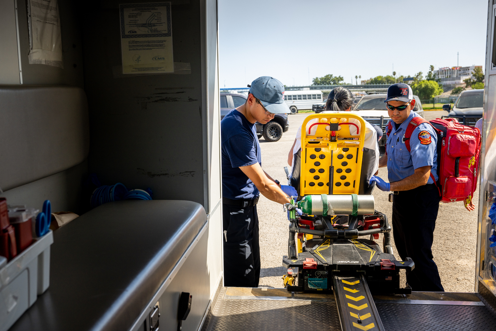 Paramedics attend to a person in a yellow stretcher under the bright sun