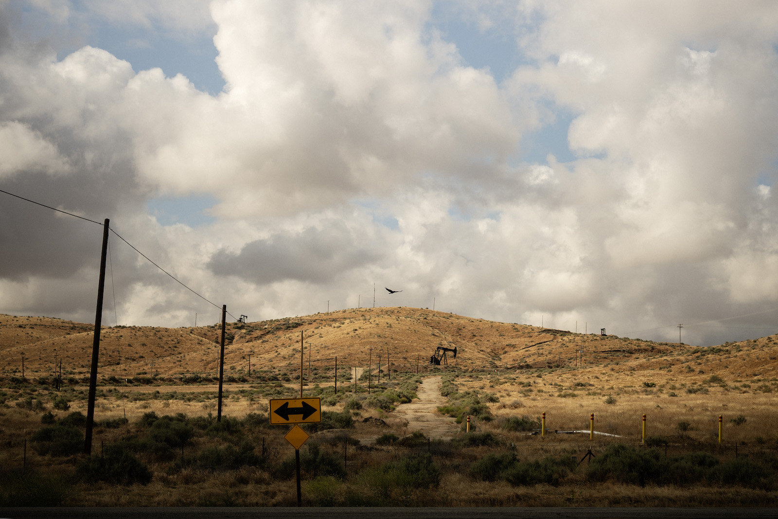 A landscape with golden hills sand a pumpjack