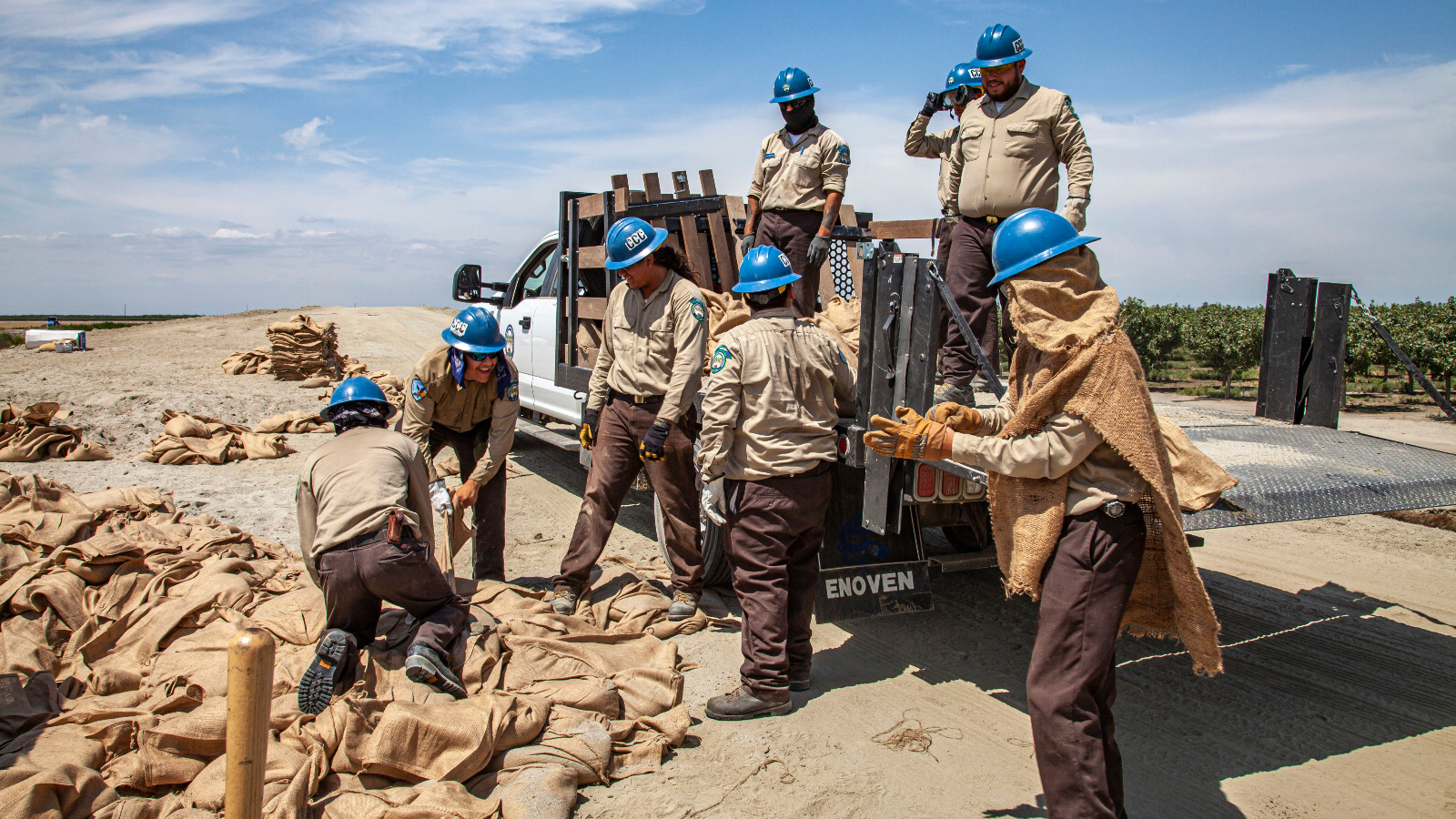 Photo of a group of people in hard hats working in a dry landscape