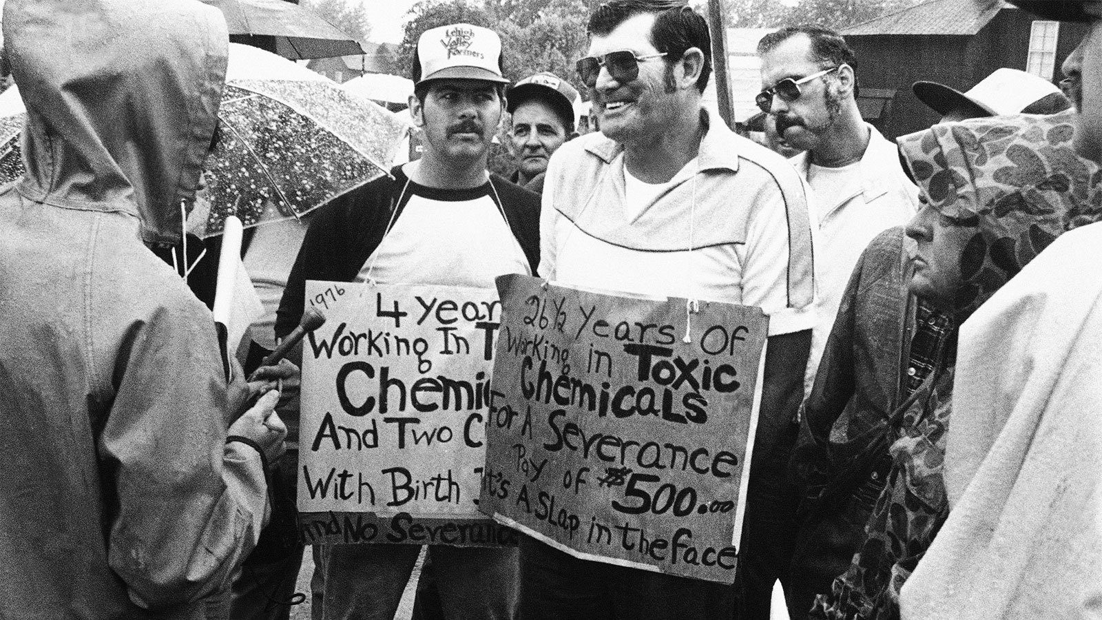 Group of people protesting working with toxic chemicals, two holding signs