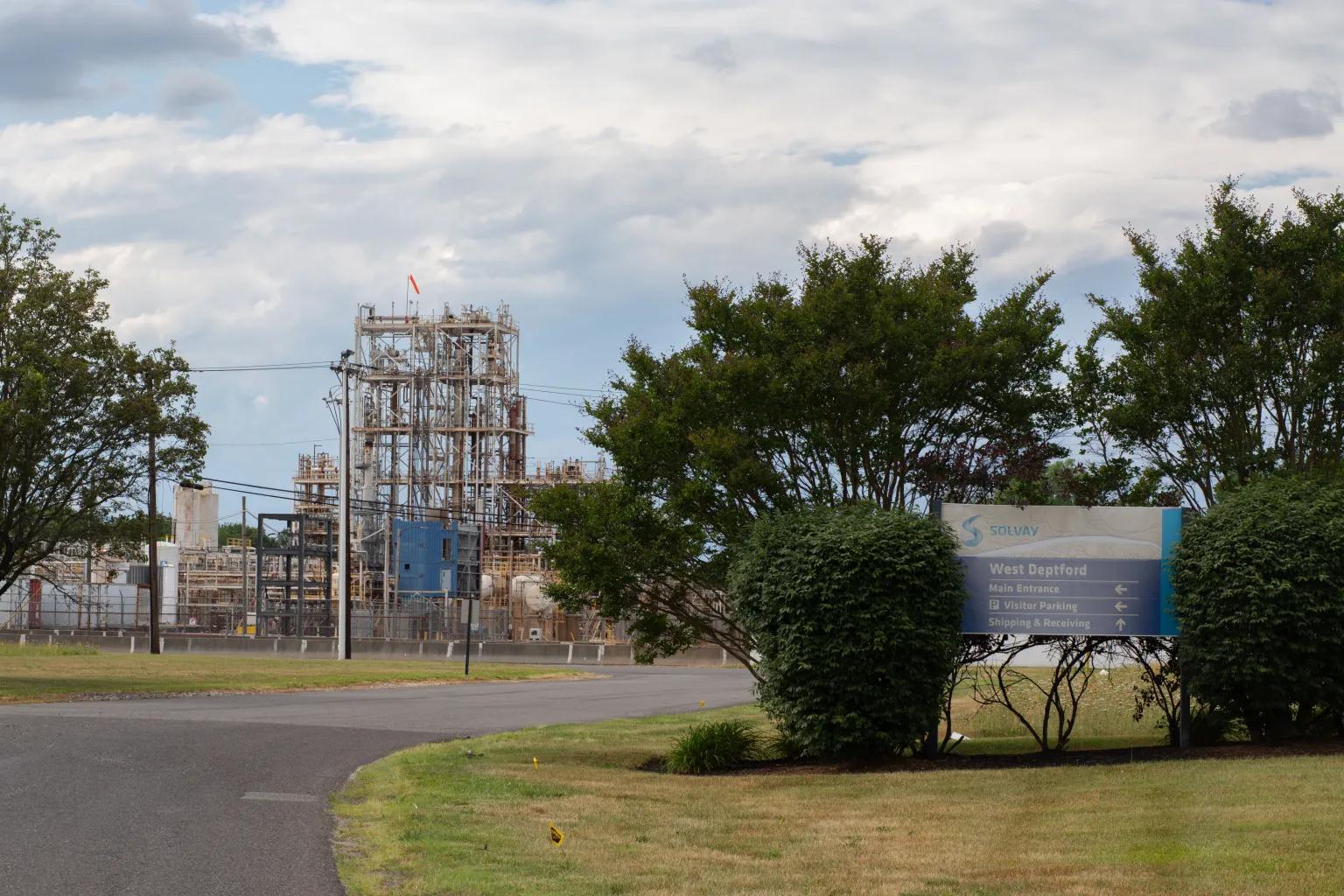 An industrial complex sits off of a road with trees.