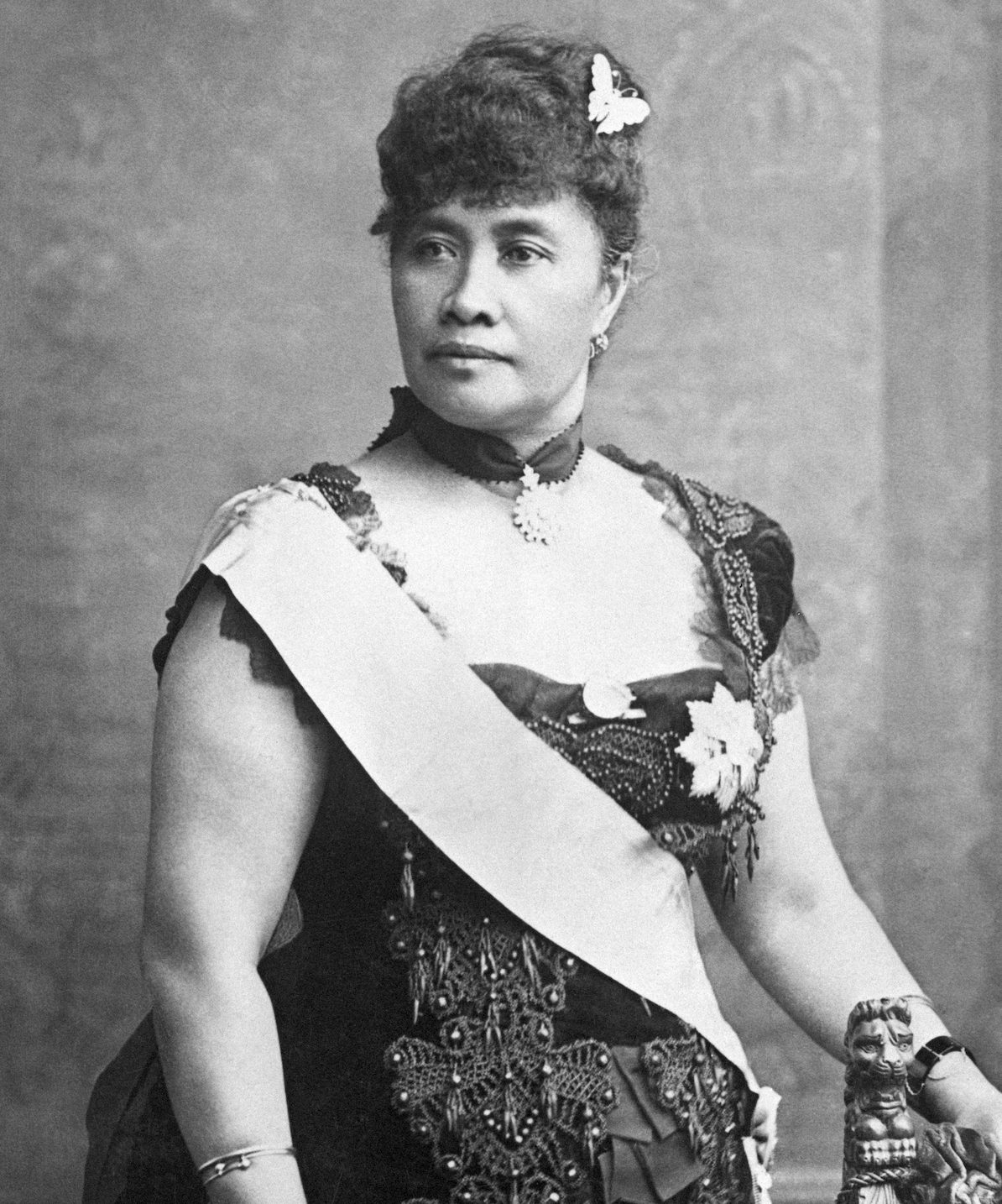 A black and white photo of a woman in regal gown and sash