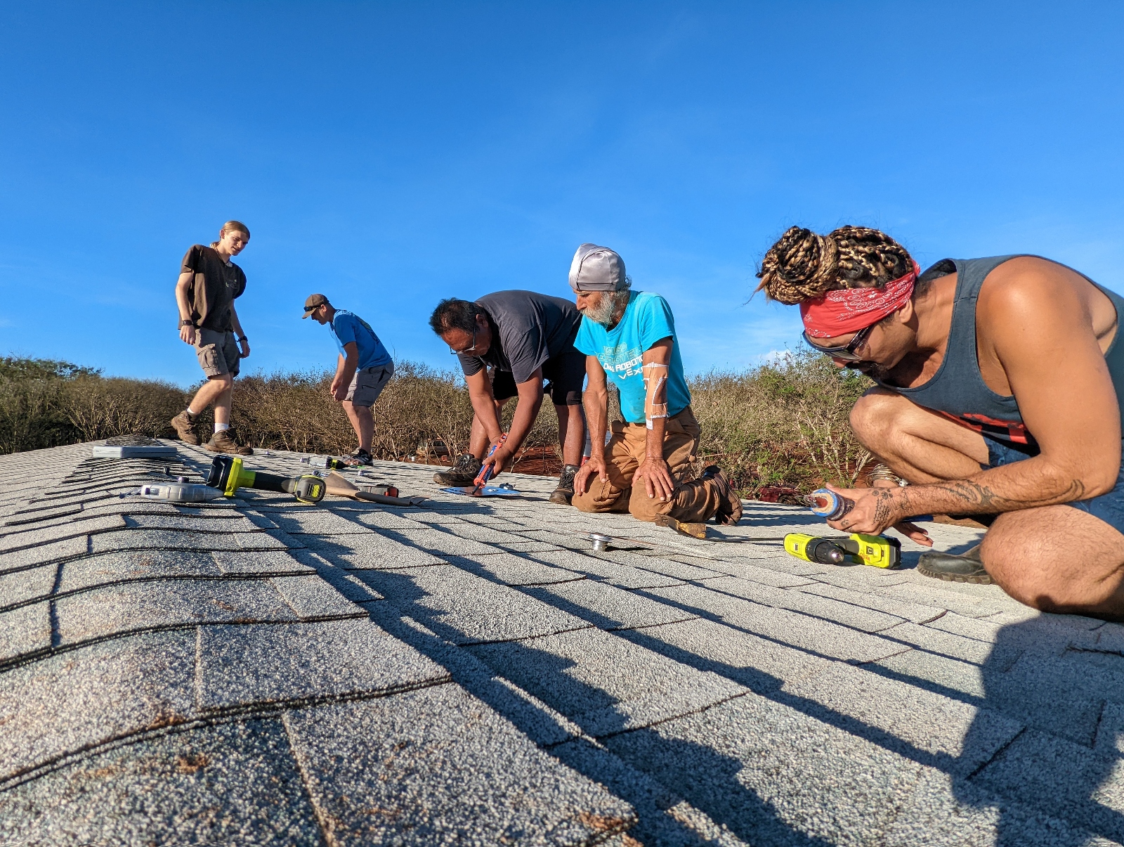 Five members of a local community work on a roof