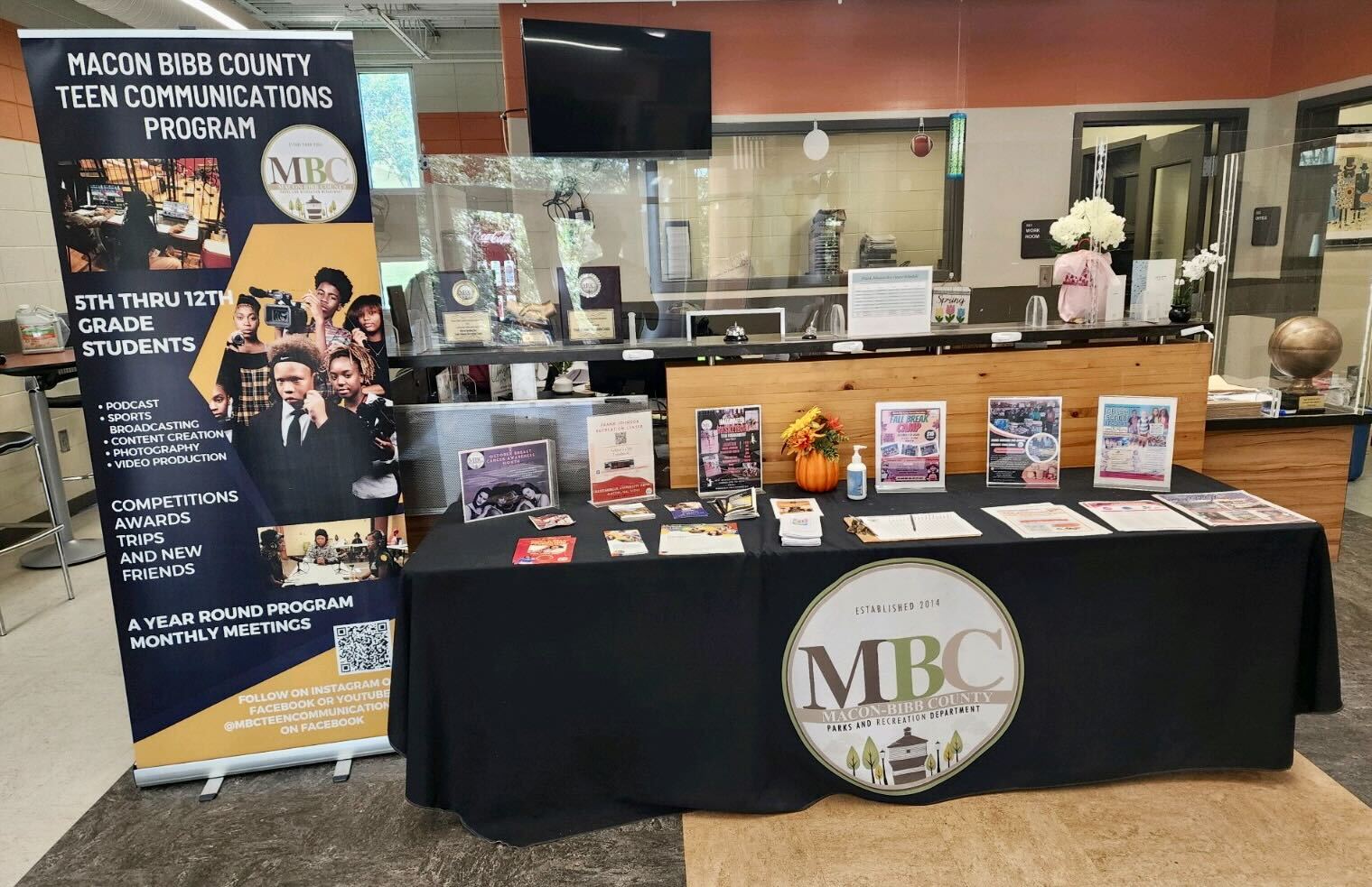 A table with a black tablecloth with lots of brochures on top of it