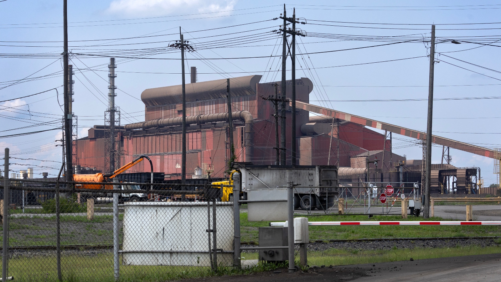 A red rusting plant sits next to an electric line