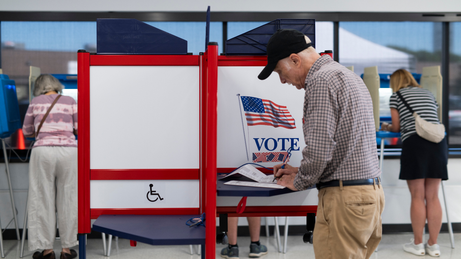 Photo of voters filling out their ballots at voting booths.