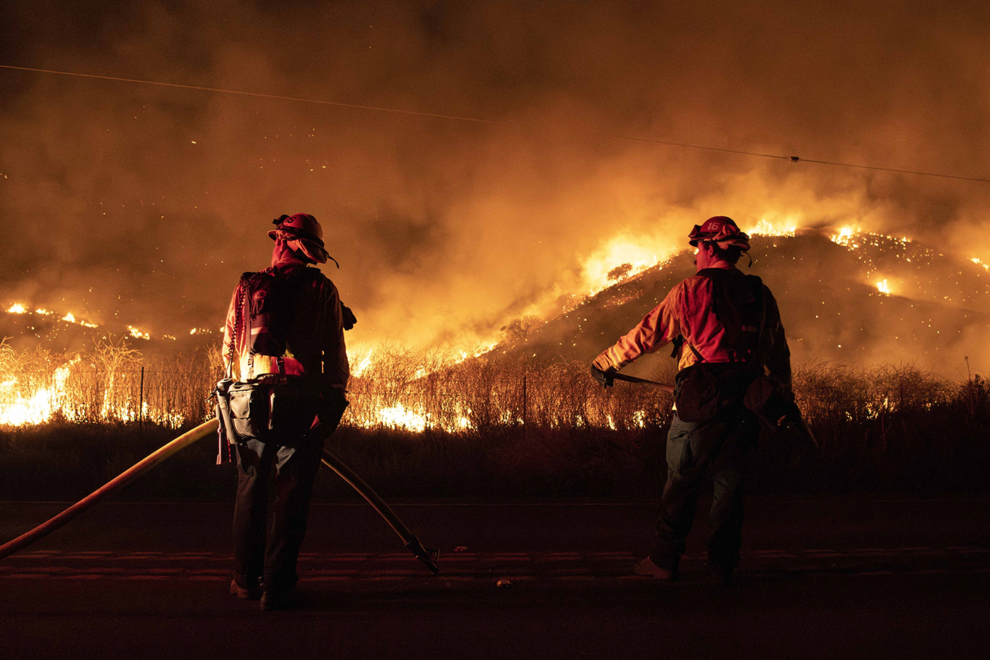 Two firefighters standing in front of an active wildfire